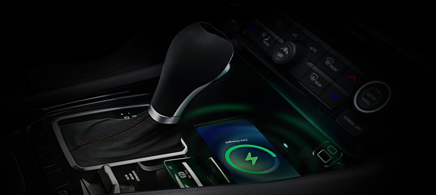 A close-up of the center console in the 2024 Jeep Compass Limited, focusing on the shifter and wireless charging pad.