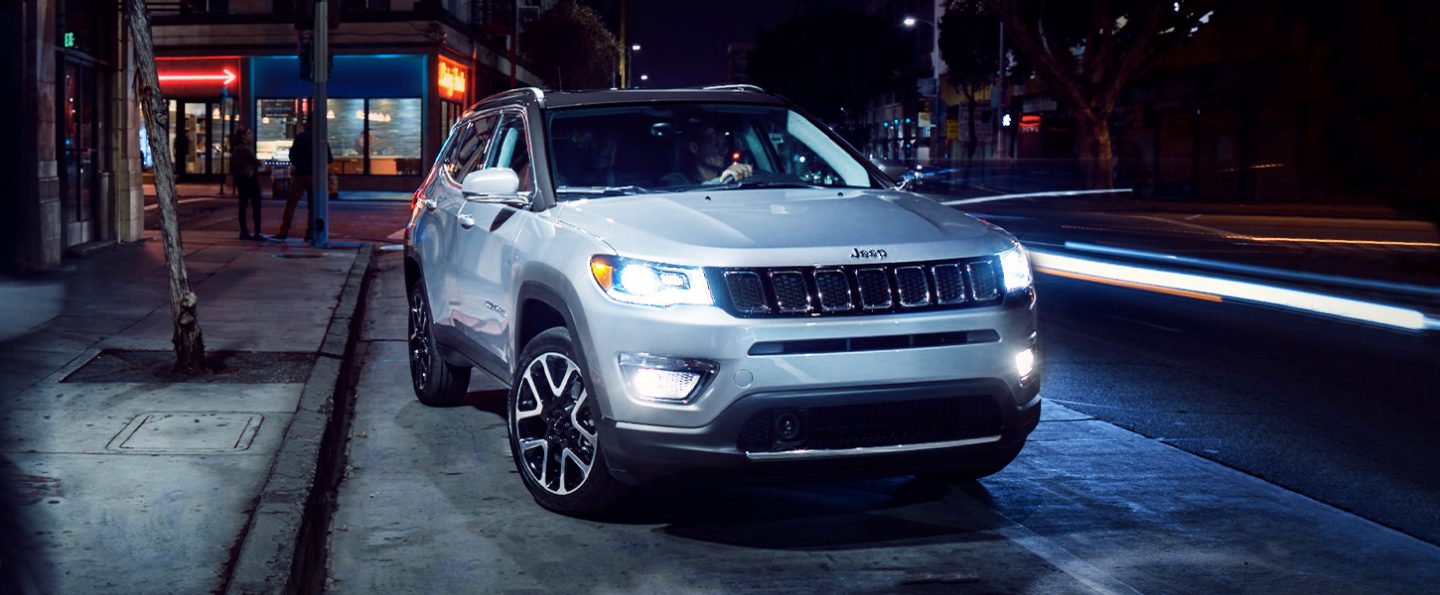 The 2020 Jeep Compass with headlamps and fog lamps illuminated.