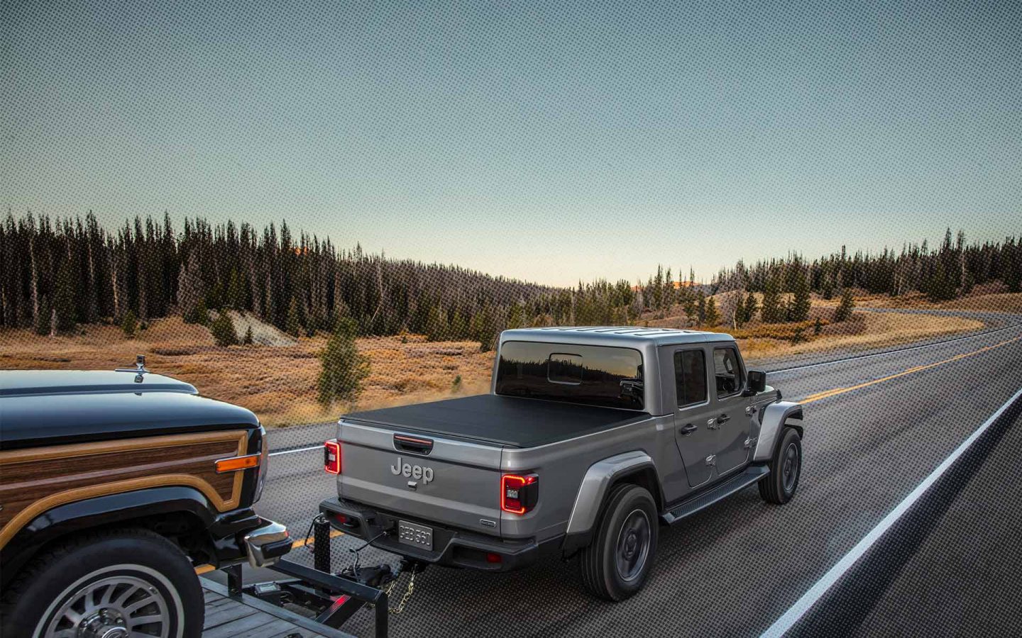 Grey Gladiator towing a boat on a 2 lane highway