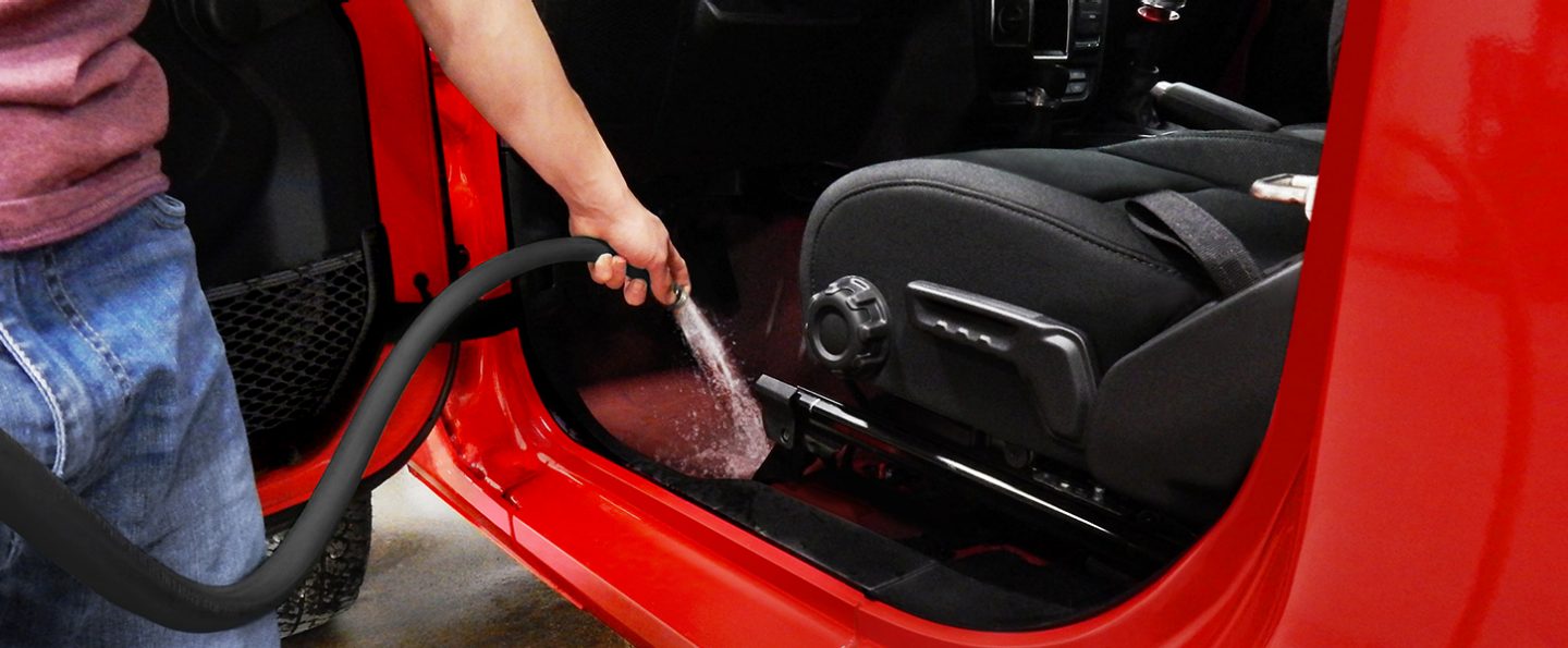 A person hosing out the interior floor of the 2020 Jeep Wrangler.