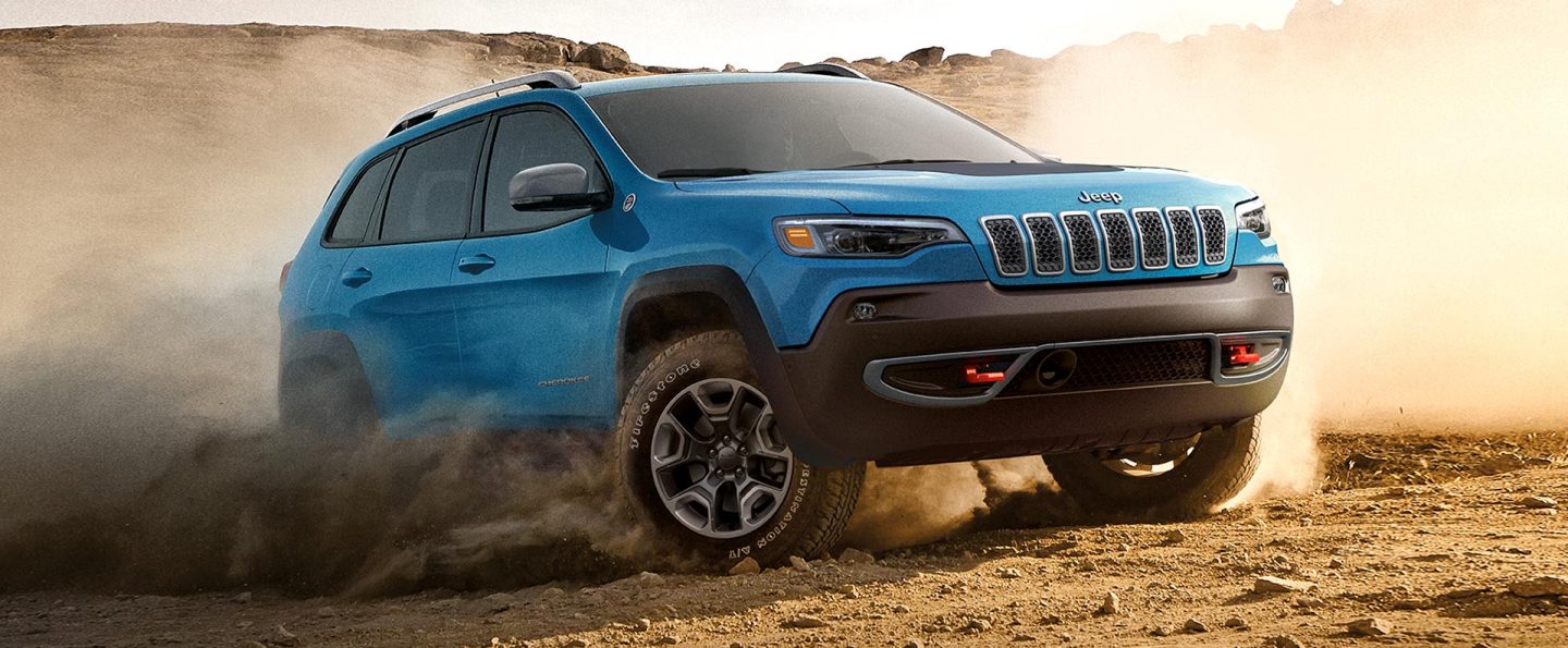 The 2021 Jeep Cherokee being driven on a dirt track with a dust cloud coming from its wheels.