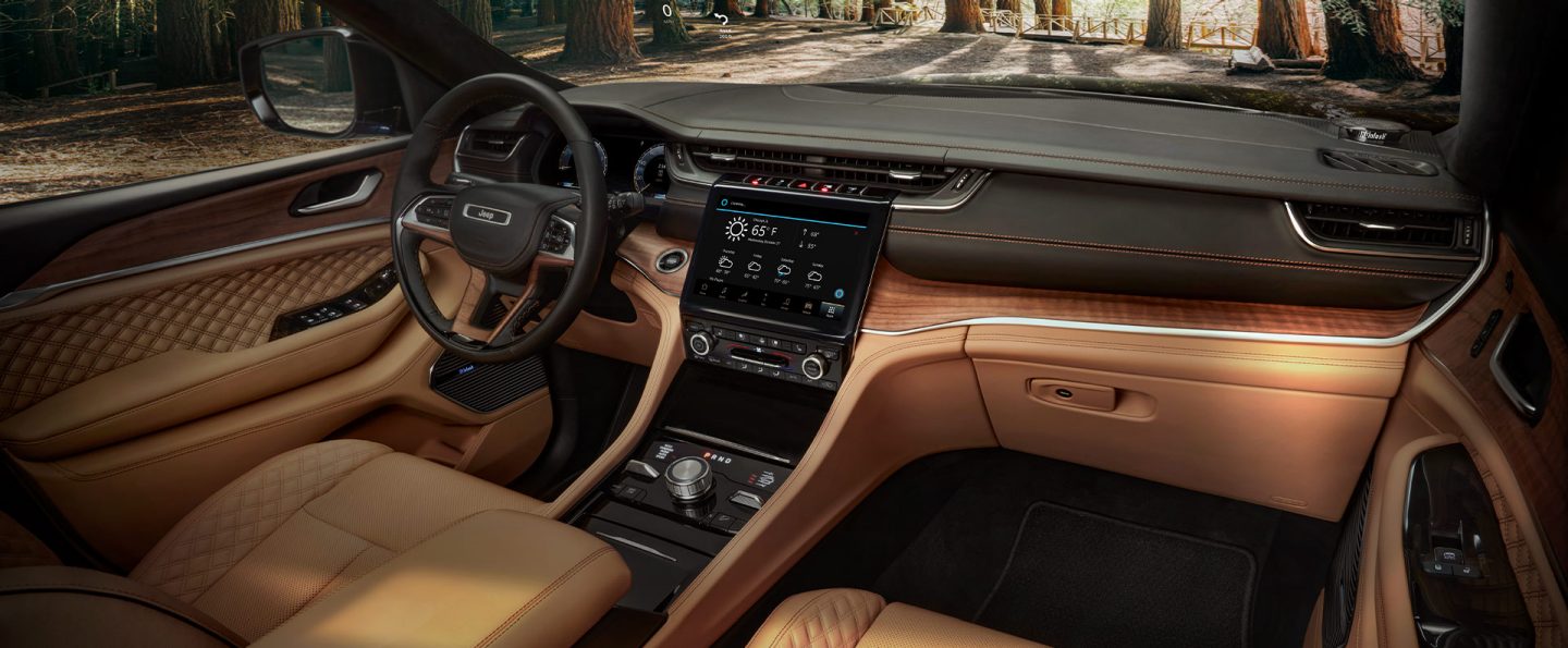 The interior of the 2021 Jeep Grand Cherokee L Summit Reserve, focusing on the front seats, entertainment center and dashboard.