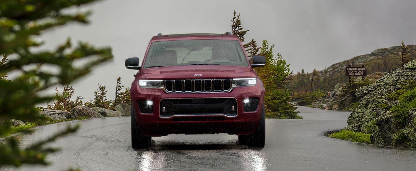 A head-on view of a 2021 Jeep Grand Cherokee L Overland being driven on a rain-slicked road.