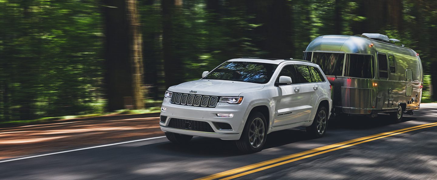 The 2021 Jeep Grand Cherokee towing a travel trailer.