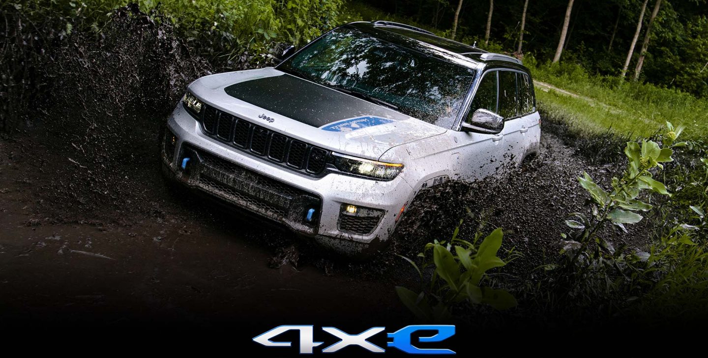 The 4xe logo. The 2022 Jeep Grand Cherokee Trailhawk 4xe being driven through a mud puddle. 