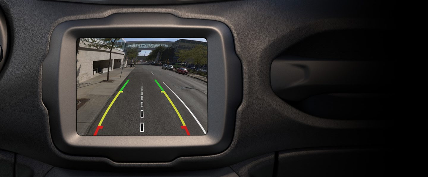 A close-up of the touchscreen in the 2022 Jeep Renegade displaying the area behind the vehicle, with parking guidelines overlaid on the screen.