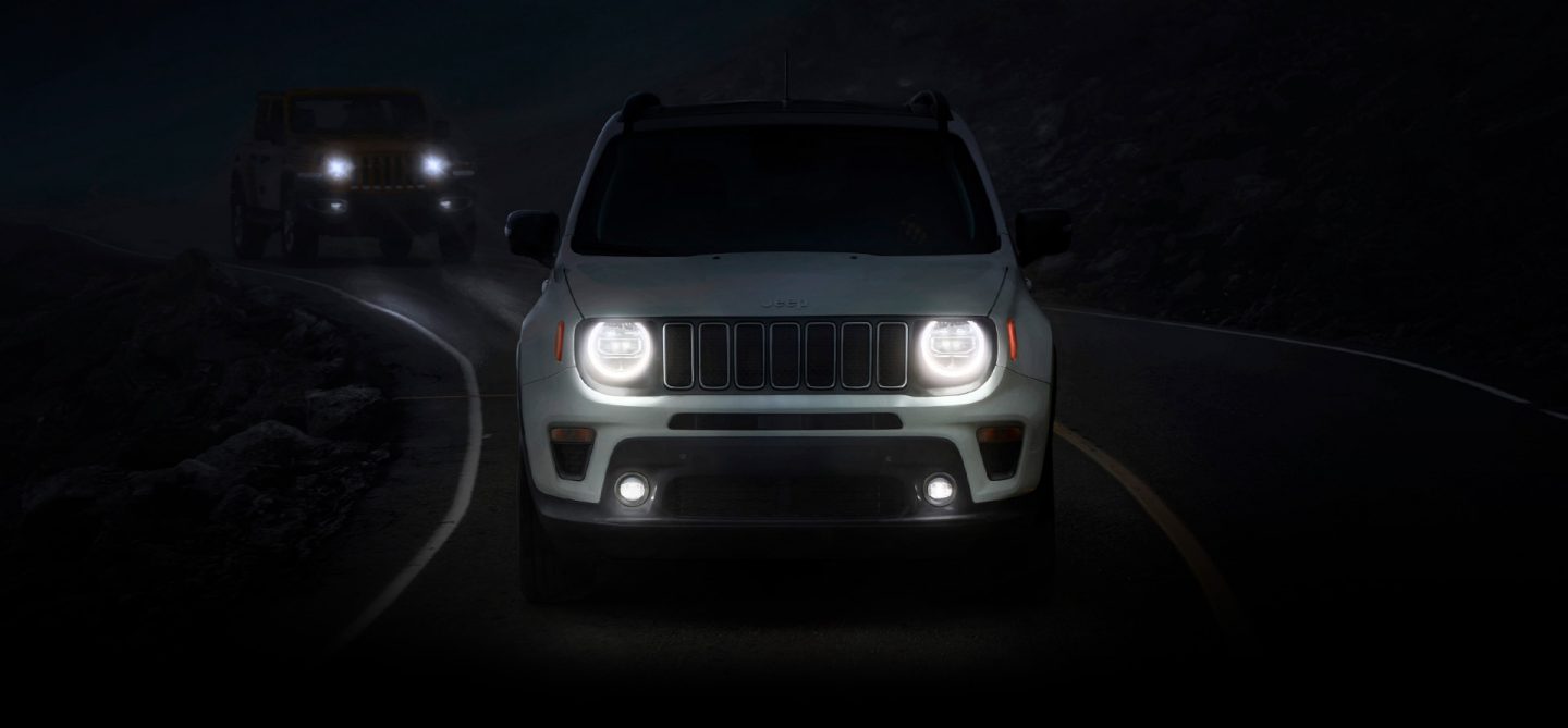 The 2022 Jeep Renegade Limited rounding a curve in the road at night, with its headlamps and fog lamps lit.