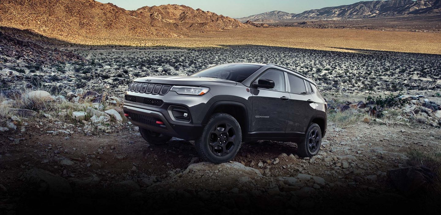 A 2023 Jeep Compass Trailhawk crawling over large and small rocks and stones off-road.