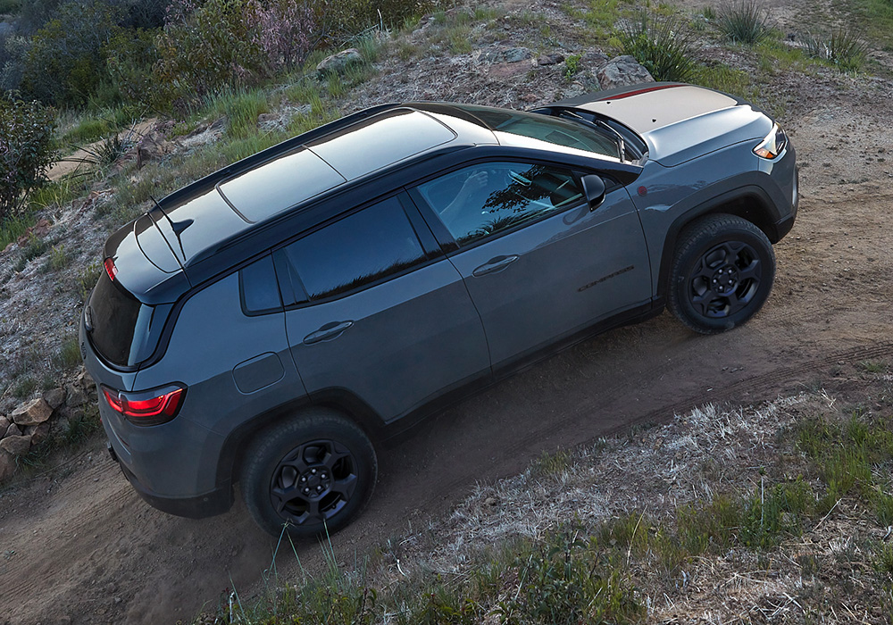 A 2023 Jeep Compass Trailhawk ascending a steep dirt trail off-road.
