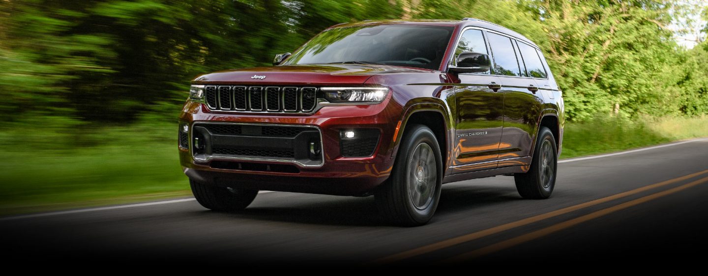 The 2023 Jeep Grand Cherokee Overland being driven on a road with the trees in the background blurred to indicate the vehicle's speed.
