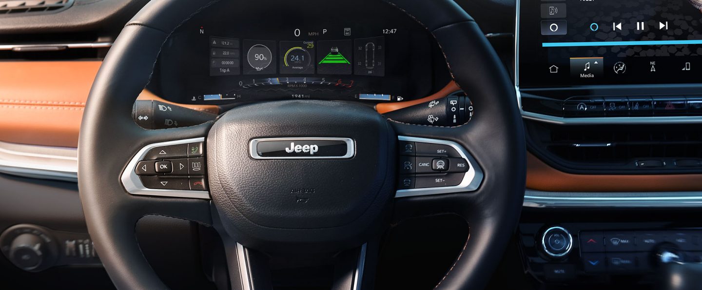 The steering wheel and Digital Cluster in the 2025 Jeep Compass Limited displaying the vehicle's oil life, average fuel economy, distance from the preceding vehicle and the tire pressure on all four tires.