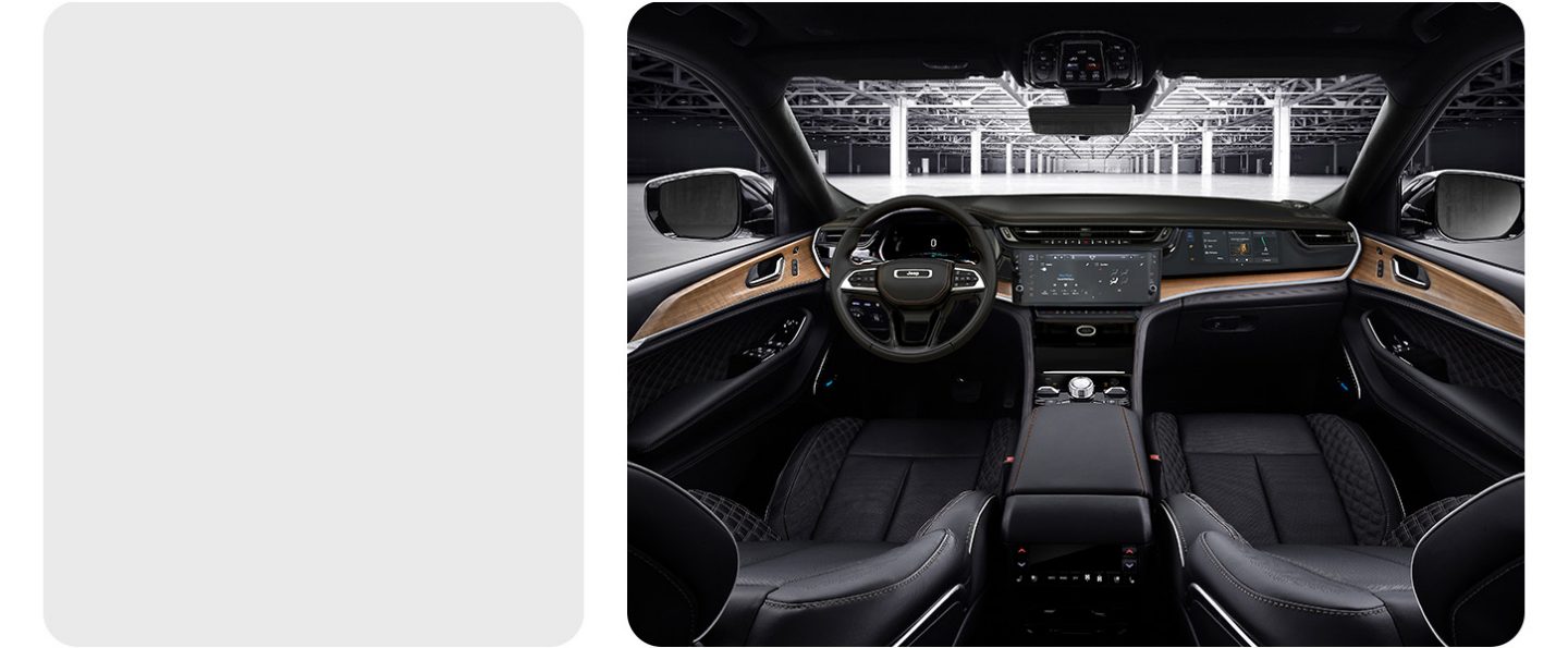 The interior of a 2026 Jeep Grand Cherokee Summit focusing on the front seats, steering wheel, Uconnect touchscreen, Front Passenger Interactive Display and center console controls.