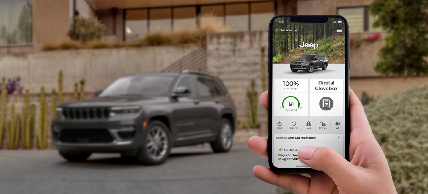 In the foreground, a hand holding a smartphone displaying the Jeep Connect app. In the background, a 2022 Jeep Grand Cherokee L.