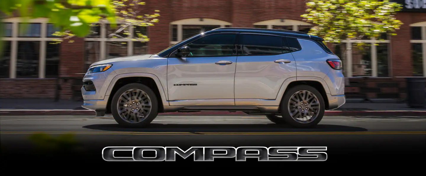 The 2022 Jeep Compass High Altitude being driven down a street past a row of brick buildings.