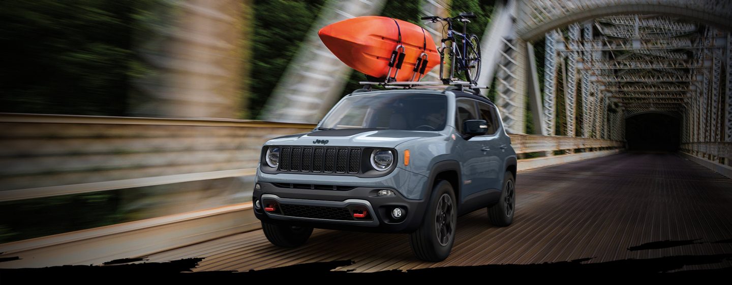 The 2023 Jeep Renegade Trailhawk being driven over a bridge with a kayak and a mountain bike secured to its roof rack.