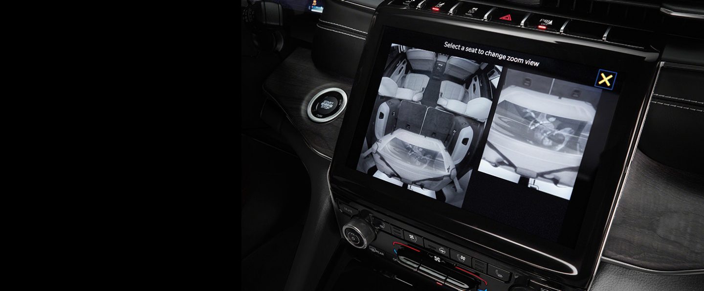 The Uconnect touchscreen in the 2024 Jeep Grand Cherokee displaying the output of the rear-seat monitoring camera, with a split-screen of both the second and third rows.